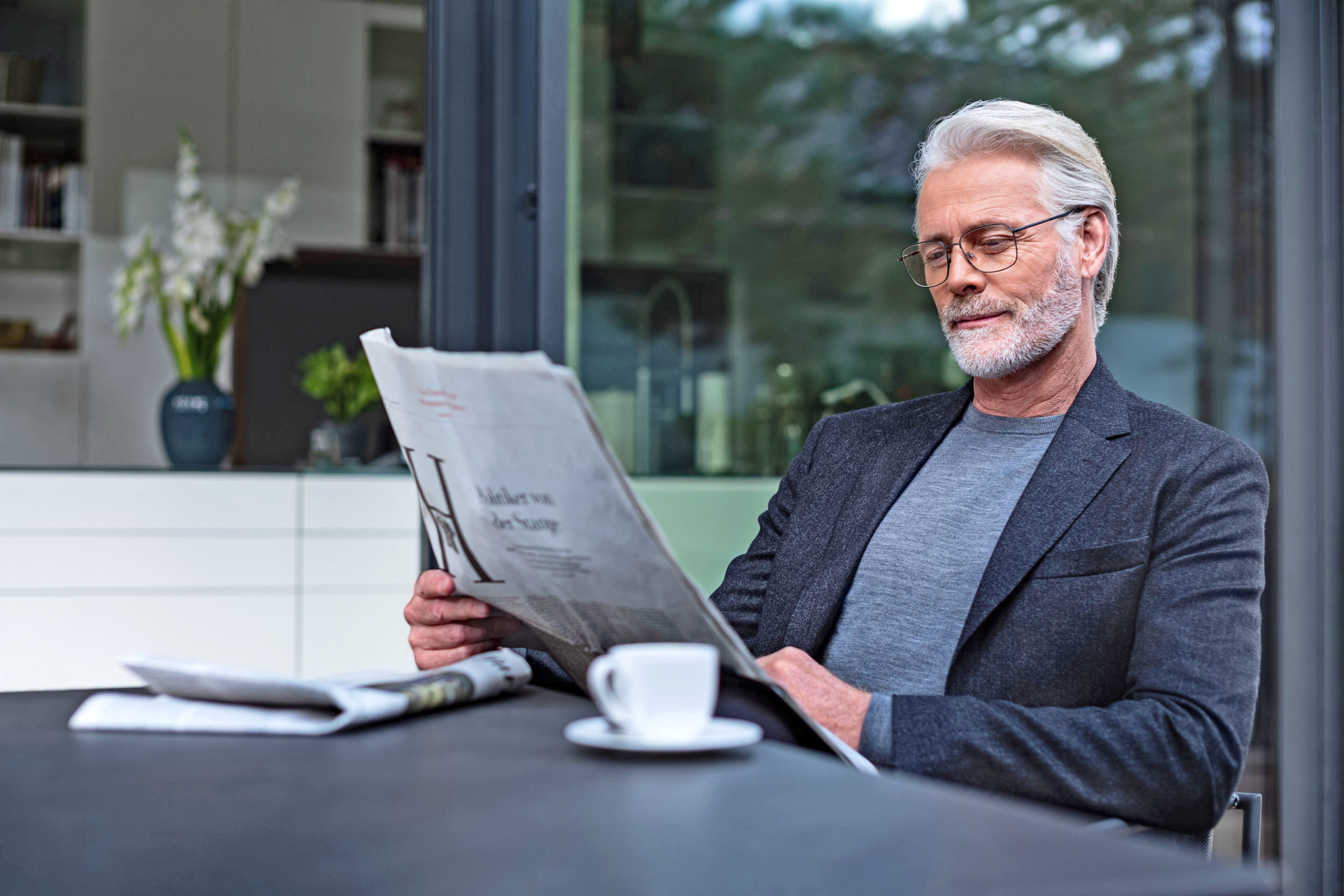 Mann mit Brille liest Zeitung bei einer Tasse Kaffee