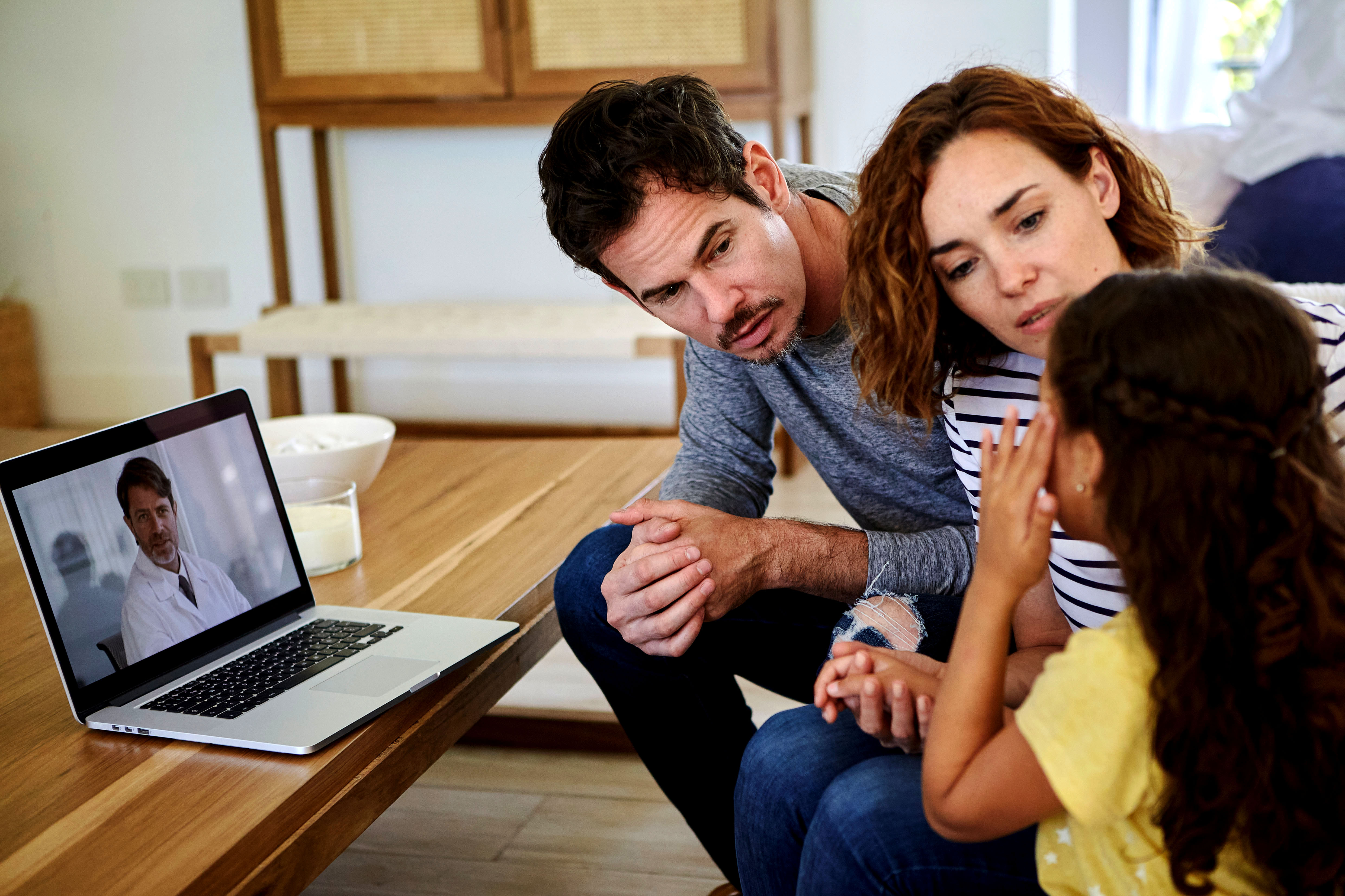 Junge Familie vor dem Notebook bei Online-Sprechstunde